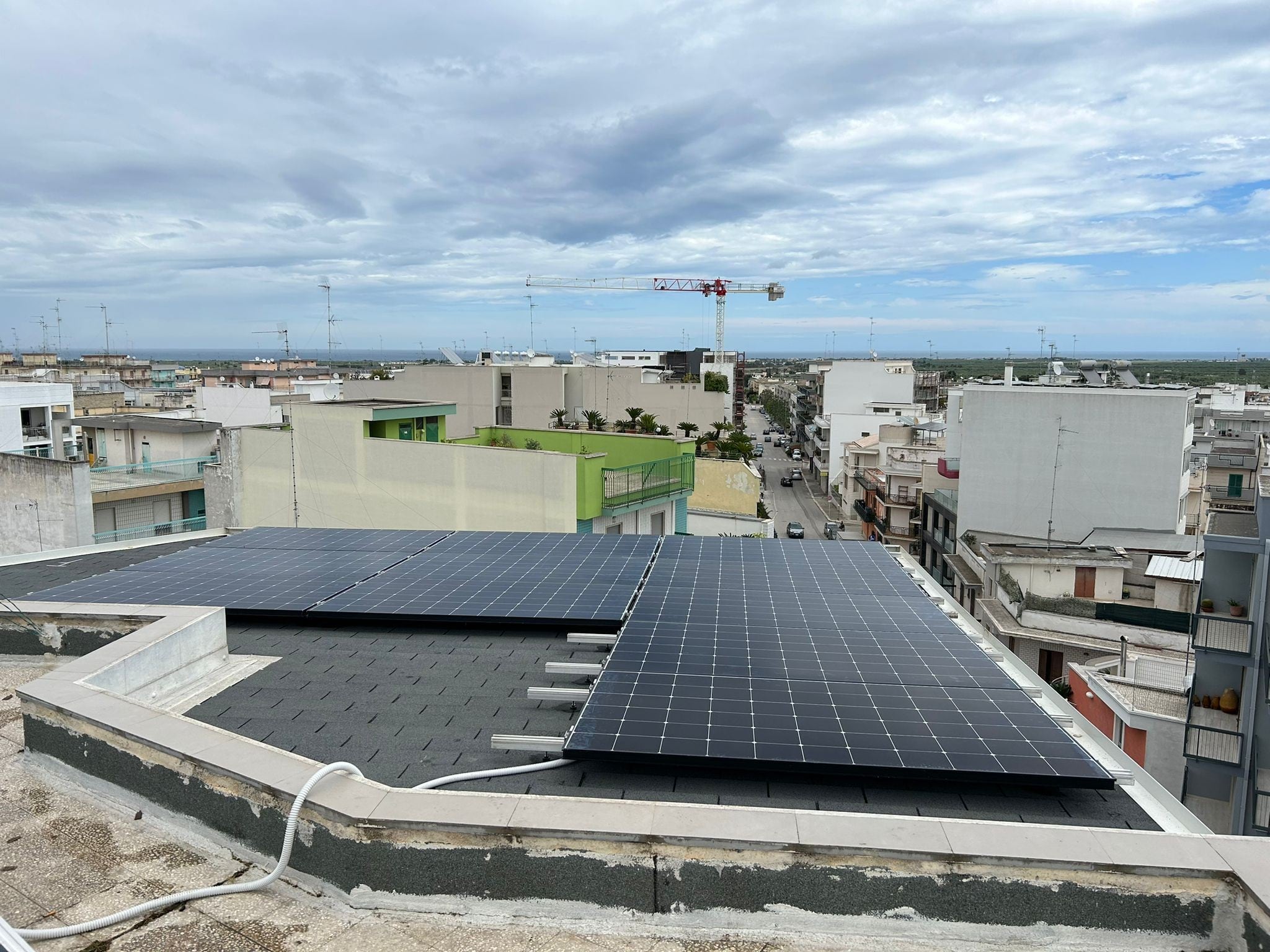 Pannelli solari su tetto, vista città e mare.