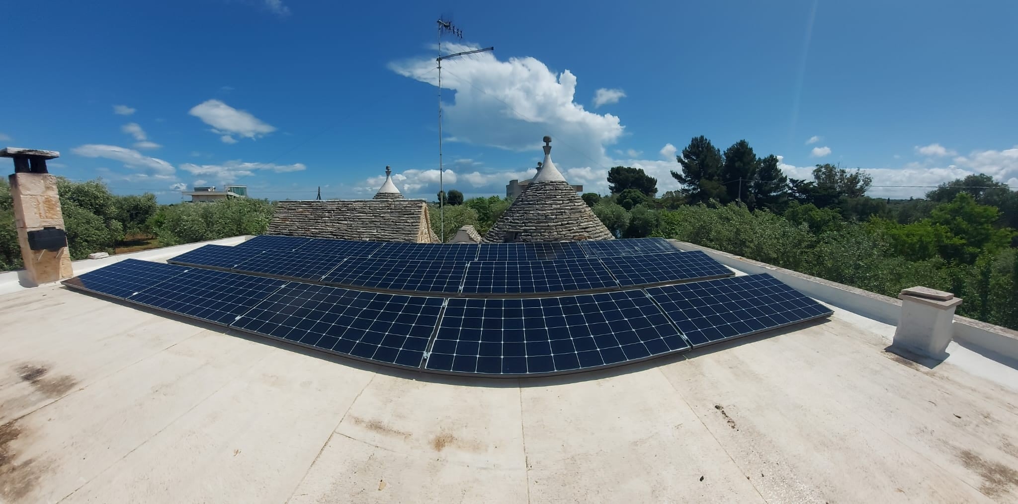Pannelli solari su tetto di trulli, cielo sereno.