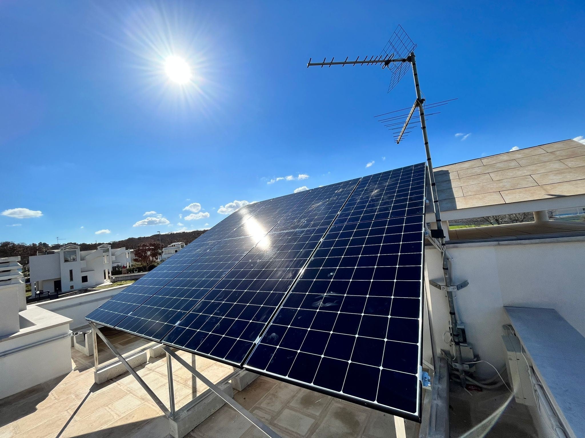 Pannelli solari su tetto con antenna, cielo sereno e sole.